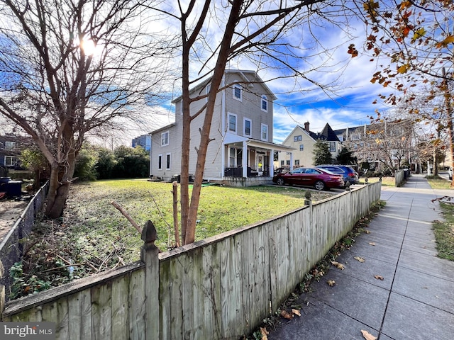 view of side of property with covered porch and a lawn