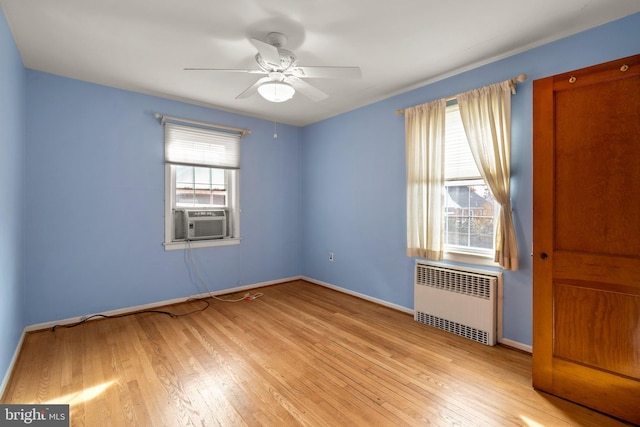 unfurnished room featuring plenty of natural light, ceiling fan, light wood-type flooring, and radiator