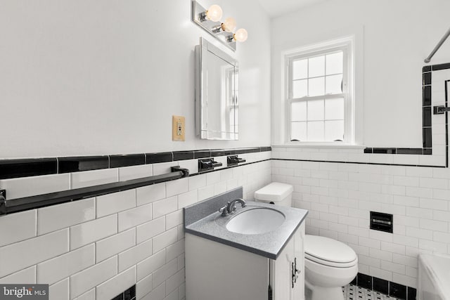 bathroom featuring vanity, tile walls, and toilet