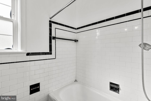 bathroom featuring tiled shower / bath combo and tile walls