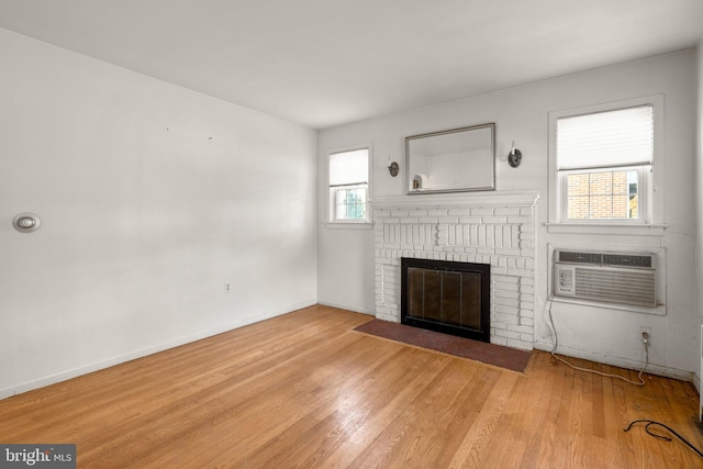 unfurnished living room featuring light hardwood / wood-style floors, a fireplace, and a wall unit AC