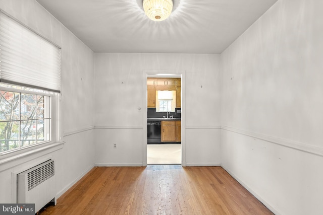 spare room with radiator, light hardwood / wood-style flooring, and sink