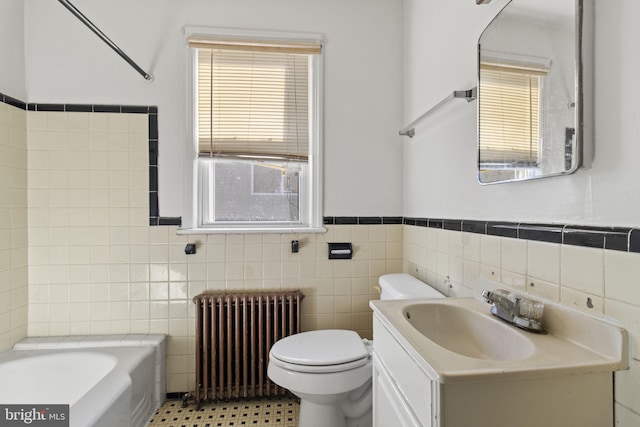 bathroom with vanity, toilet, tile walls, radiator heating unit, and a tub