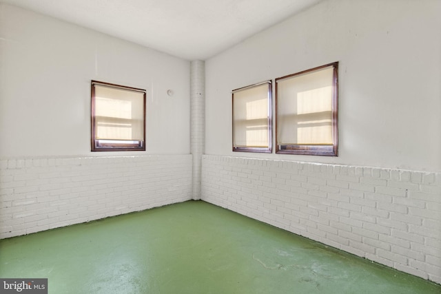 empty room with concrete floors and brick wall