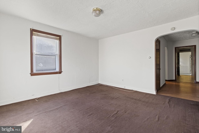 spare room with dark hardwood / wood-style floors and a textured ceiling