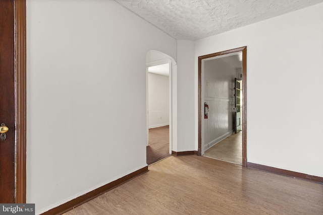 unfurnished room with hardwood / wood-style floors and a textured ceiling