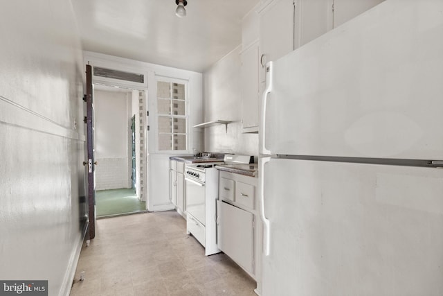 kitchen with white cabinets, white appliances, wall chimney range hood, and sink