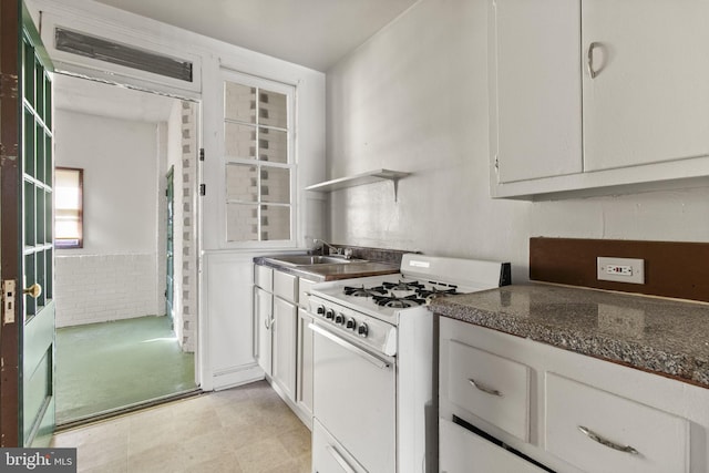 kitchen featuring white cabinetry, white range with gas stovetop, and sink