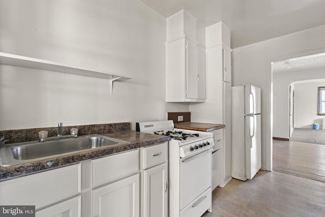 kitchen with white appliances, white cabinetry, and sink