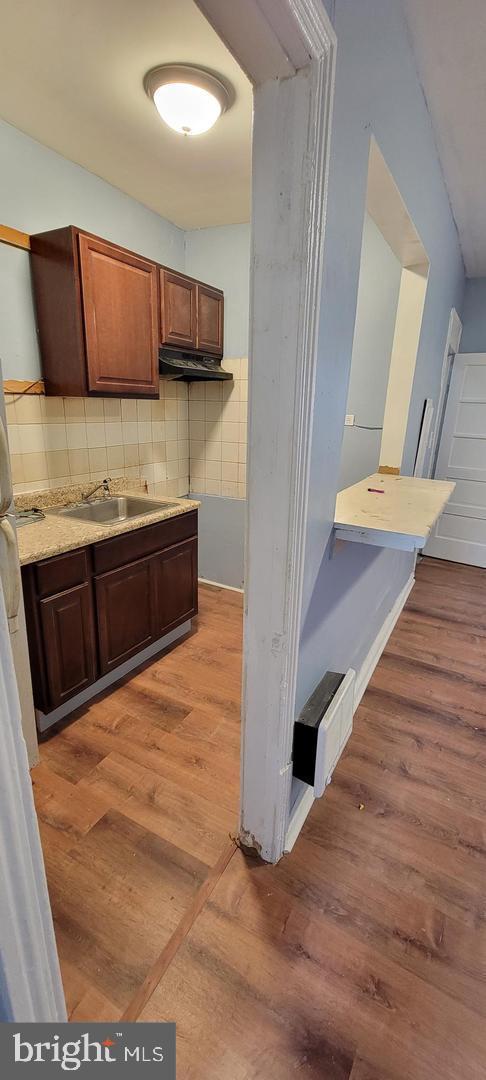 kitchen with sink, backsplash, and light hardwood / wood-style flooring