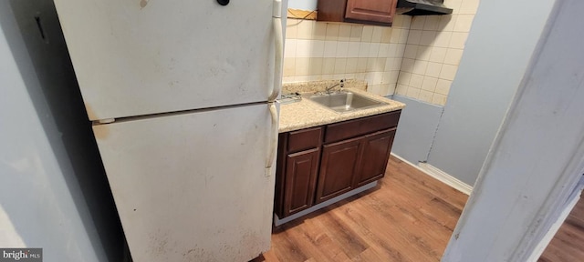 kitchen with white refrigerator, sink, light wood-type flooring, tasteful backsplash, and dark brown cabinets