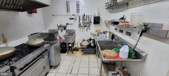 kitchen with light tile patterned floors, tile walls, and ventilation hood