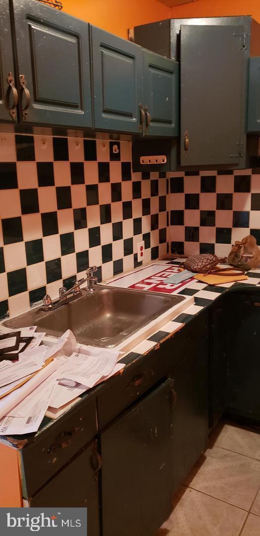 kitchen featuring decorative backsplash, light tile patterned floors, and sink