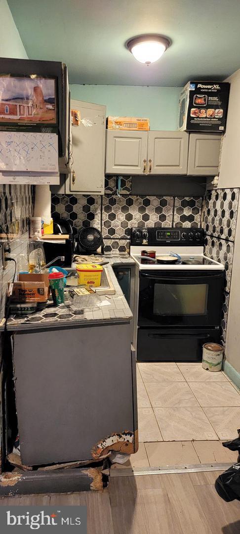 kitchen with white electric range oven, white cabinetry, backsplash, and light hardwood / wood-style flooring