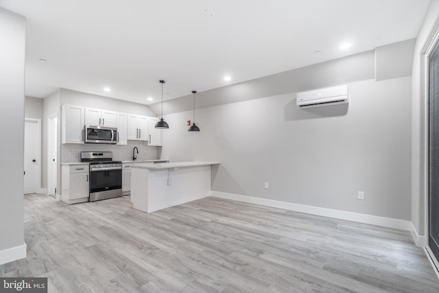 kitchen with tasteful backsplash, white cabinetry, decorative light fixtures, stainless steel appliances, and light hardwood / wood-style flooring