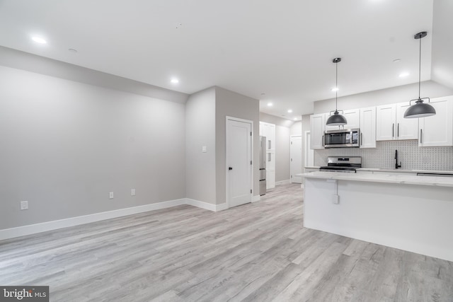 kitchen featuring tasteful backsplash, light wood-type flooring, stainless steel appliances, and white cabinetry