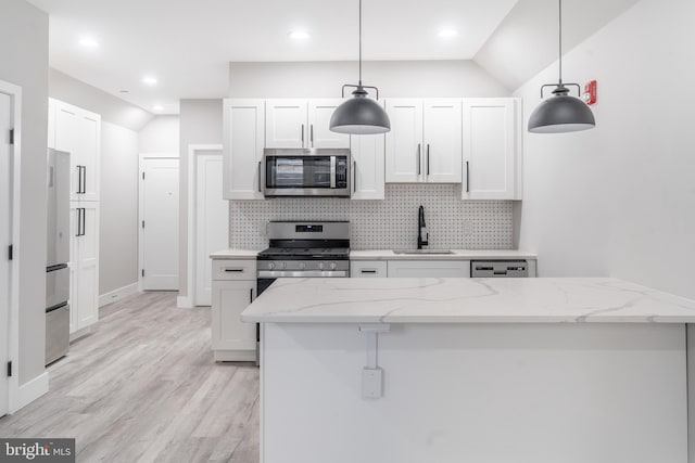 kitchen with sink, stainless steel appliances, vaulted ceiling, and decorative light fixtures