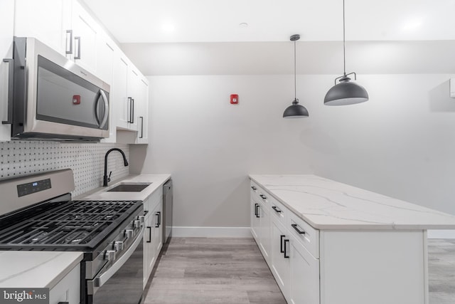 kitchen with sink, light hardwood / wood-style floors, backsplash, decorative light fixtures, and stainless steel appliances