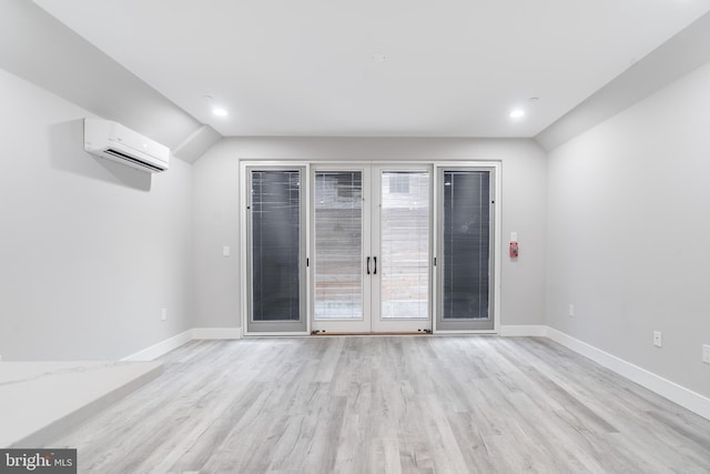 spare room with french doors, an AC wall unit, and light wood-type flooring