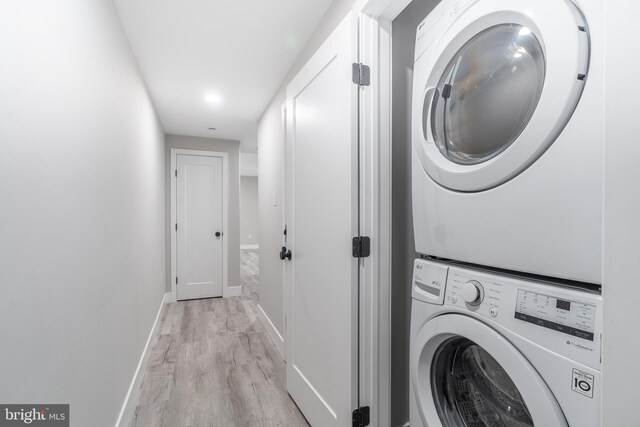 clothes washing area featuring stacked washer / dryer and light wood-type flooring