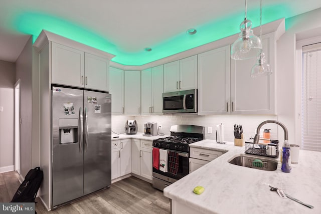 kitchen featuring white cabinets, pendant lighting, light wood-type flooring, and stainless steel appliances