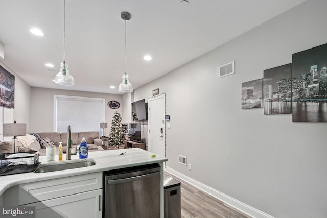 kitchen with decorative light fixtures, stainless steel dishwasher, light hardwood / wood-style floors, and sink