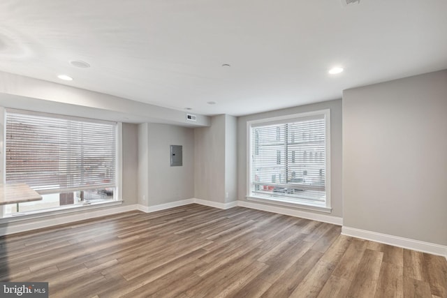 unfurnished room featuring electric panel and hardwood / wood-style flooring