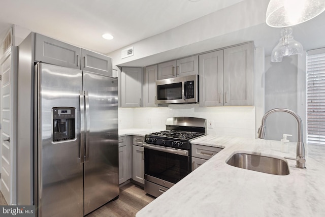 kitchen with gray cabinets, sink, stainless steel appliances, and hanging light fixtures