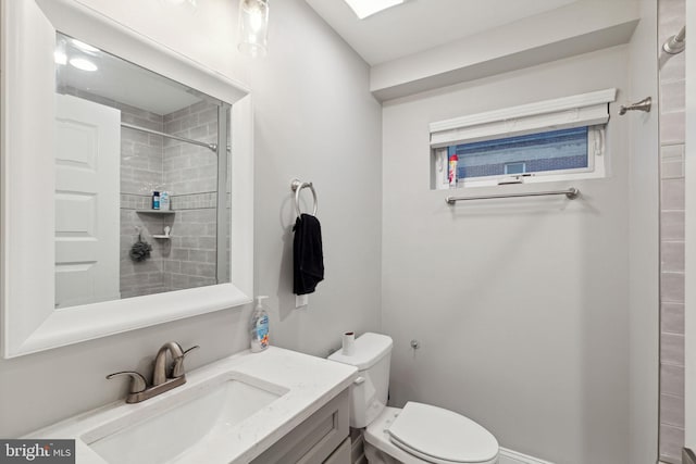 bathroom with vanity, toilet, and tiled shower