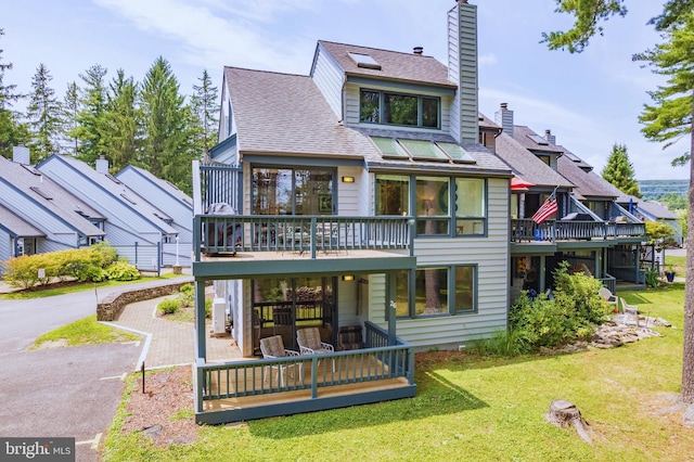 rear view of house featuring a lawn and a deck