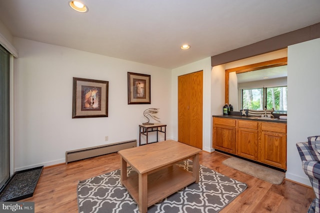 living area featuring a baseboard radiator, sink, and light hardwood / wood-style floors