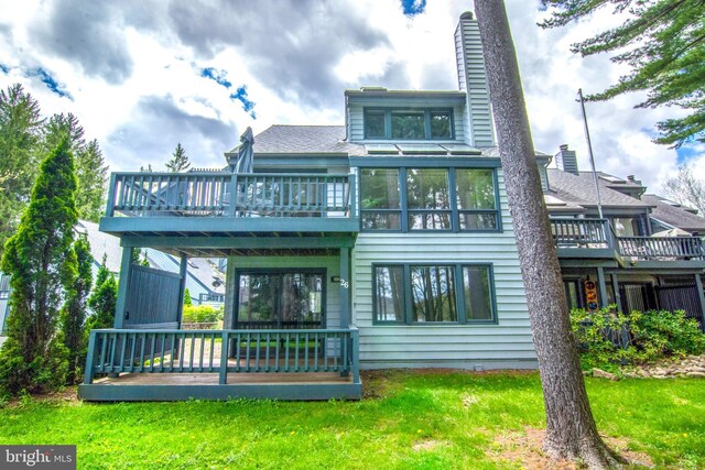 back of property with a sunroom, a yard, and a deck