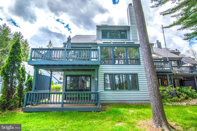 back of property with a wooden deck and a lawn