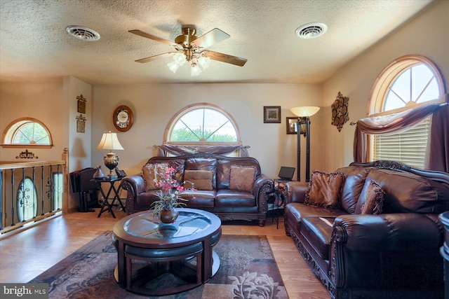 living room featuring ceiling fan, hardwood / wood-style floors, and a textured ceiling