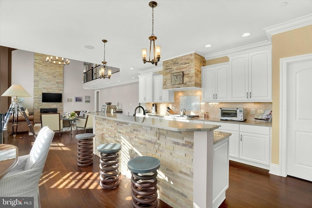 kitchen with white cabinets, pendant lighting, decorative backsplash, and a stone fireplace