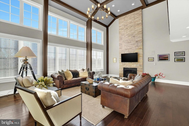 living room with dark hardwood / wood-style flooring, beamed ceiling, a towering ceiling, a chandelier, and a fireplace