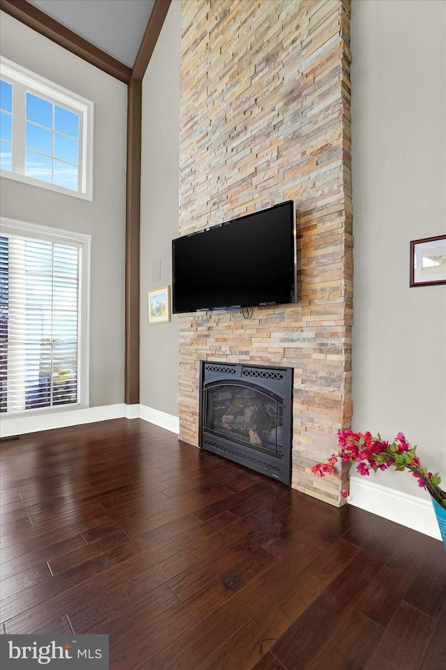 unfurnished living room featuring wood-type flooring, high vaulted ceiling, and a stone fireplace