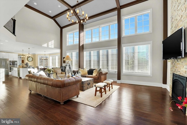 living room with beamed ceiling, a notable chandelier, a fireplace, a high ceiling, and dark hardwood / wood-style floors