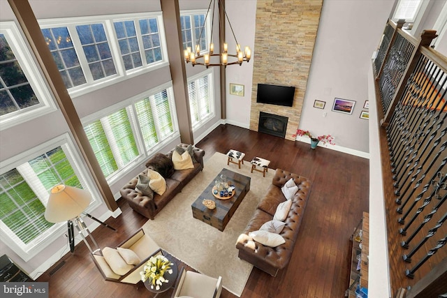 living room featuring a fireplace, a towering ceiling, dark hardwood / wood-style floors, and a notable chandelier