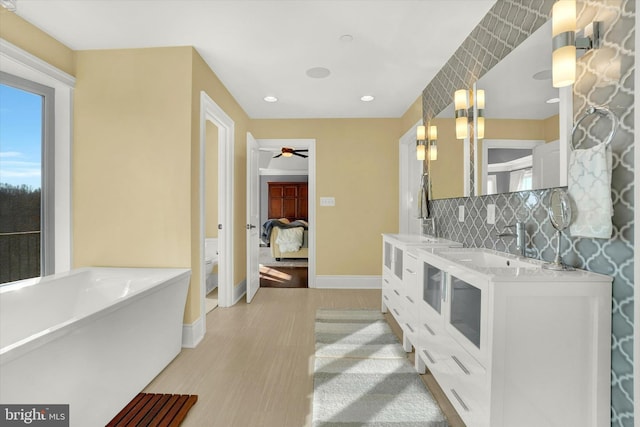 bathroom with a washtub, tasteful backsplash, toilet, vanity, and hardwood / wood-style flooring