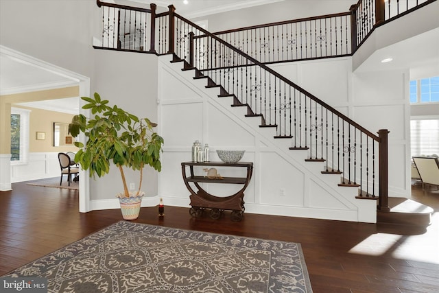 staircase with a healthy amount of sunlight, wood-type flooring, and crown molding