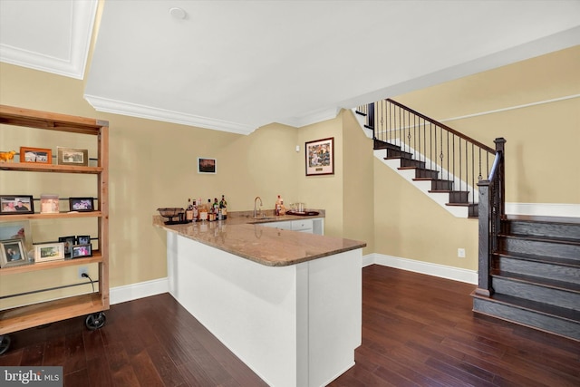 bar featuring stone counters, white cabinets, sink, crown molding, and dark hardwood / wood-style floors