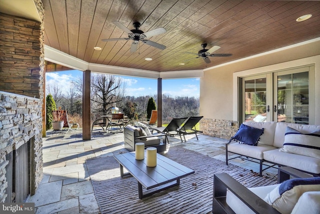 view of patio / terrace featuring an outdoor living space with a fireplace, ceiling fan, and french doors