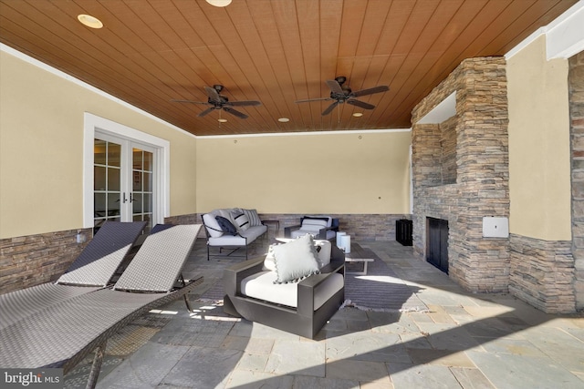 view of patio / terrace featuring an outdoor living space with a fireplace, ceiling fan, and french doors