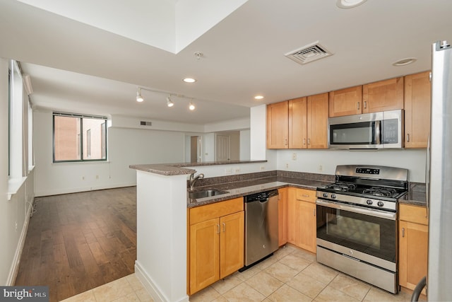 kitchen with kitchen peninsula, light hardwood / wood-style flooring, sink, and stainless steel appliances