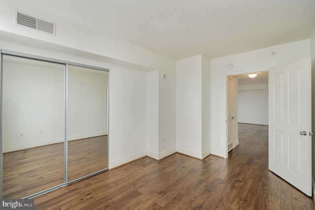 unfurnished bedroom featuring a closet and dark hardwood / wood-style floors