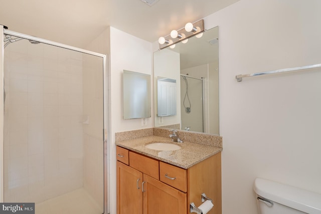 bathroom with toilet, vanity, and a shower with door