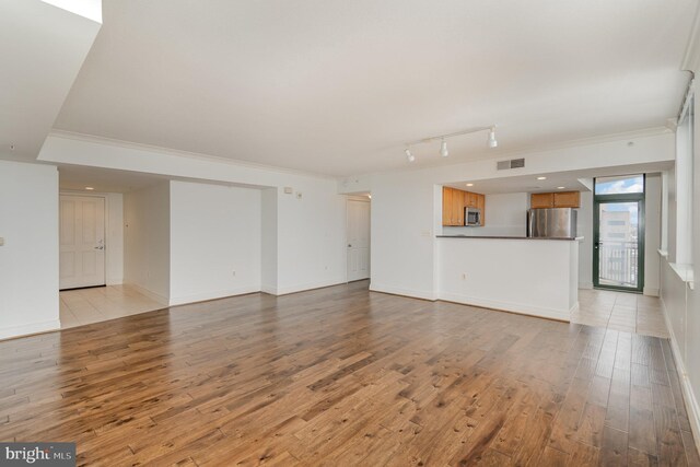 unfurnished living room with light wood-type flooring and rail lighting