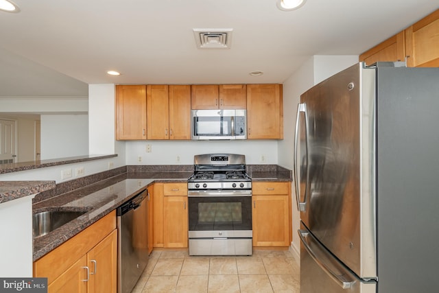 kitchen featuring sink, light tile flooring, appliances with stainless steel finishes, and dark stone counters