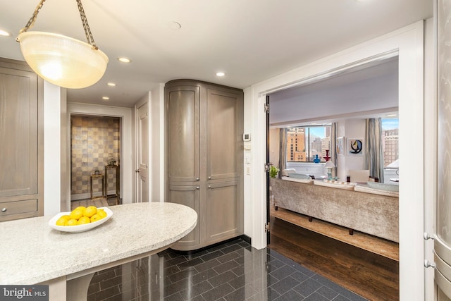 kitchen featuring dark hardwood / wood-style flooring, hanging light fixtures, and light stone countertops